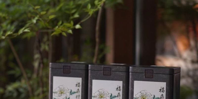 三罐贴着中文标签的白牡丹茶罐，整齐排列在桌上，背景是虚化的庭院