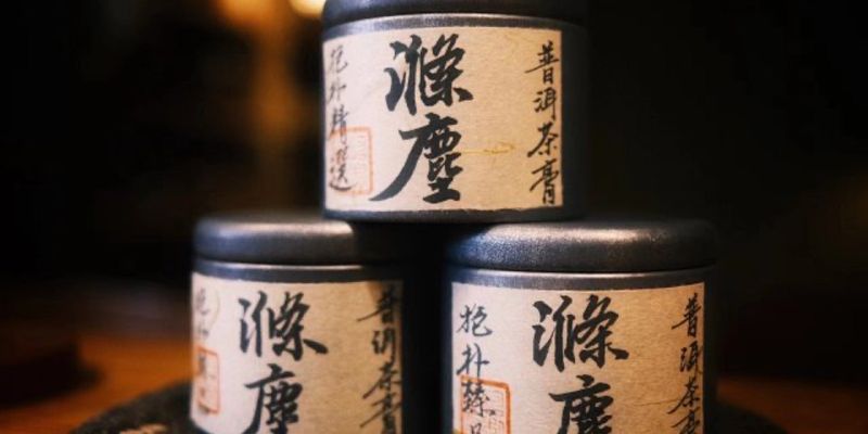 三个印有中文字样的深色小茶罐，叠成金字塔状放在深色桌面上