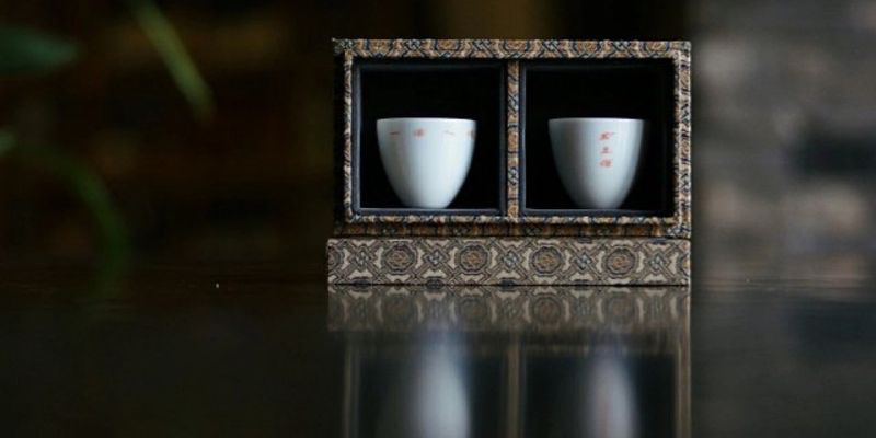 一对白瓷杯放在锦盒衬底的展示盒内