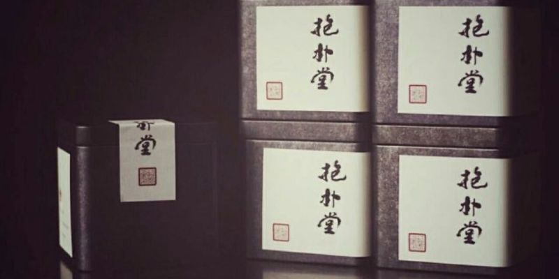 几罐深色茶罐叠放在一起，其中一罐的纸标还未完全贴牢，背景幽暗