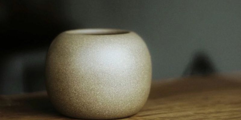 A small round beige clay vessel resting on a wooden table