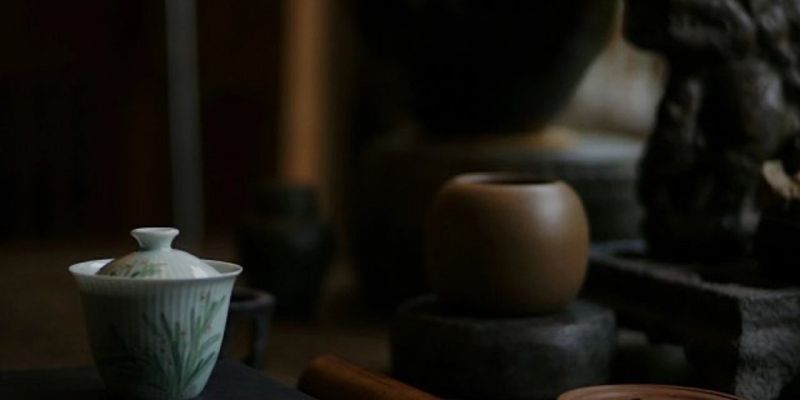 A small hand-painted porcelain tea bowl with floral motifs, set in a dim, candle-lit room
