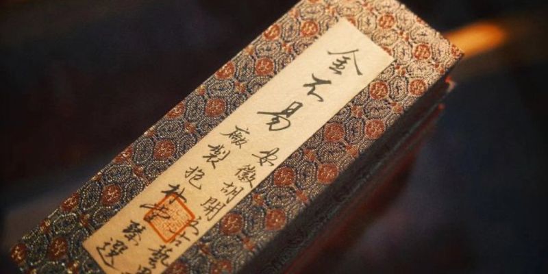A long rectangular ink stick wrapped in ornate brocade packaging with calligraphy detail